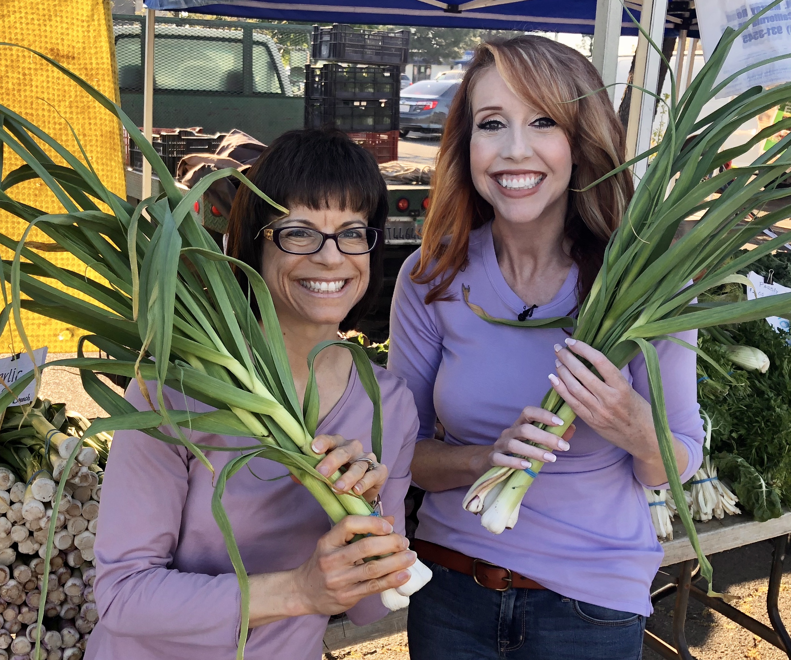 Timaree and Tracy holding green garlic
